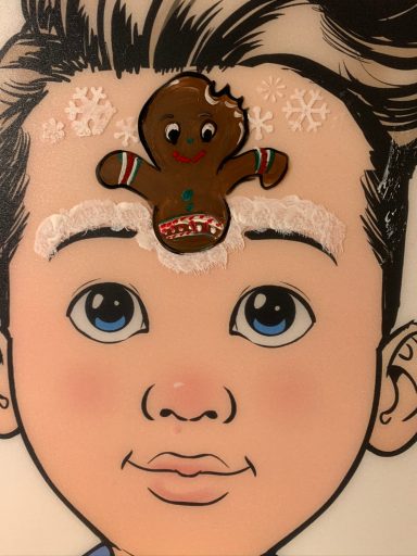 Junge mit großen blauen Augen und einem Lebkuchenmann auf der Stirn.