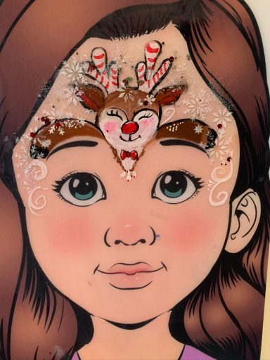 Kindergesicht mit festlichem Weihnachtsdesign auf der Stirn, inklusive Rentier und Süßigkeiten.